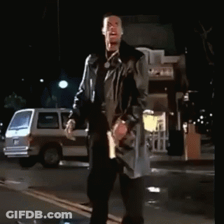 A Man In A Trench Coat Stands On A Street At Night GIF