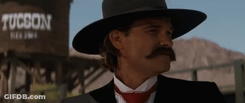 A Man In A Tucson Hat Stands In Front Of A Water Tank GIF