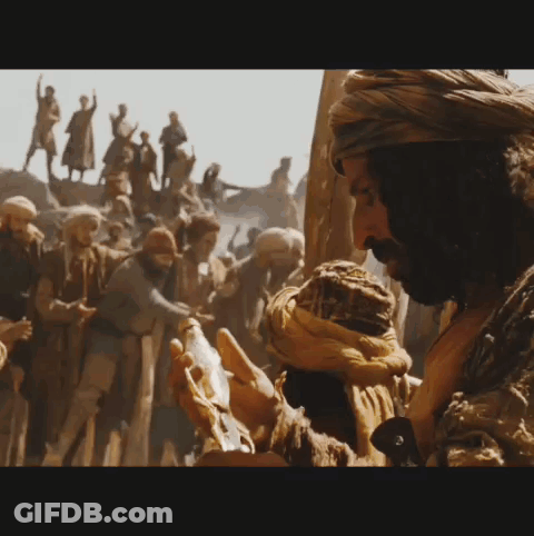A Man In A Turban Is Holding Something In Front Of A Crowd Of People GIF