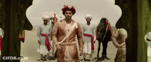 A Man In A Turban Is Standing In Front Of A Group Of Men And A Horse GIF