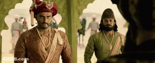 A Man In A Turban Is Standing Next To Another Man In A Costume . GIF