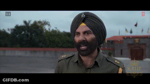 A Man In A Turban With A Beard Is Standing In Front Of A Building GIF