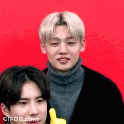 A Man In A Turtleneck Sweater Is Giving A Thumbs Up Sign Next To Another Man In A Black Jacket . GIF