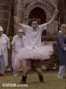 A Man In A Tutu Is Dancing In A Field . GIF