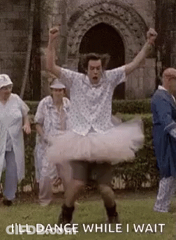 A Man In A Tutu Is Dancing In A Park While A Group Of People Watch . GIF