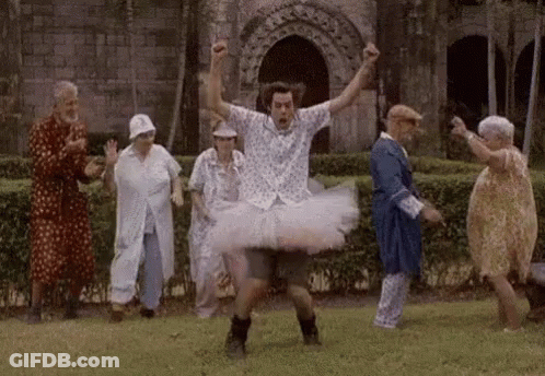A Man In A Tutu Is Dancing With A Group Of Elderly People In A Park . GIF