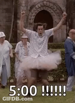 A Man In A Tutu Is Jumping In The Air While A Group Of People Watch . GIF