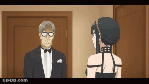 A Man In A Tuxedo And A Woman In A Black Dress Are Standing Next To Each Other GIF