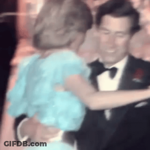 A Man In A Tuxedo And A Woman In A Blue Dress Are Dancing . GIF