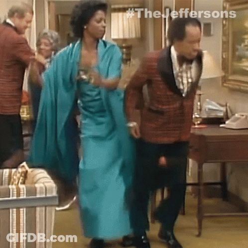 A Man In A Tuxedo And A Woman In A Blue Dress Are Dancing In A Living Room GIF