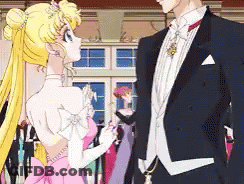 A Man In A Tuxedo And A Woman In A Pink Dress Are Standing Next To Each Other GIF