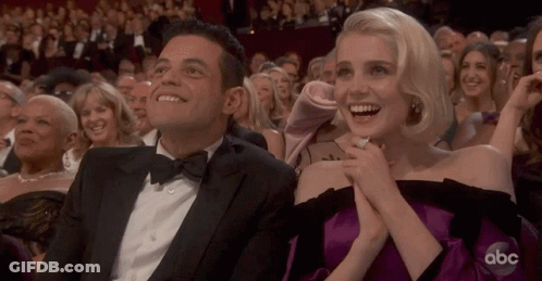 A Man In A Tuxedo And A Woman In A Purple Dress Are Sitting In The Audience At An Abc Awards Show GIF
