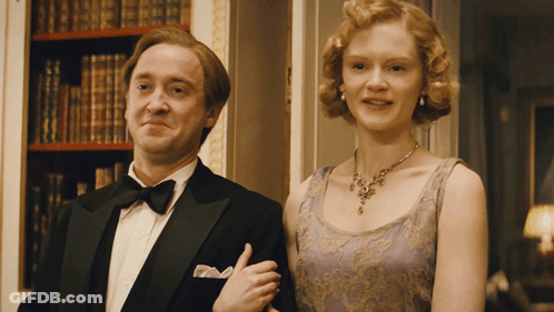 A Man In A Tuxedo And A Woman In A Purple Dress Pose For A Picture GIF