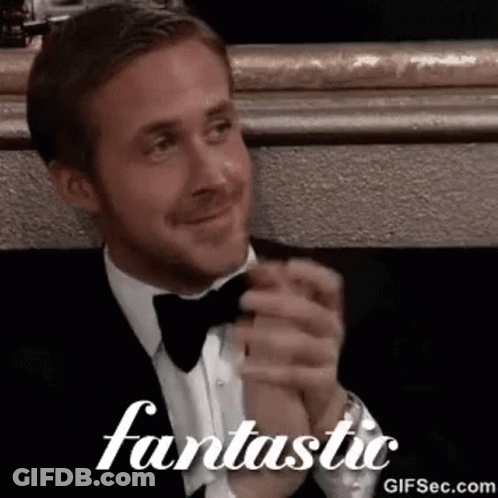 A Man In A Tuxedo And Bow Tie Is Clapping His Hands In Front Of A Mirror . GIF