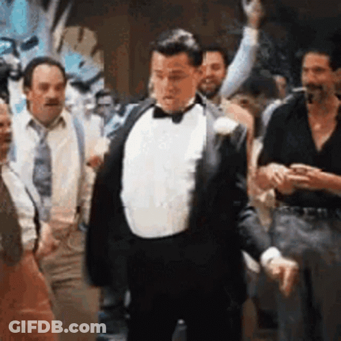 A Man In A Tuxedo And Bow Tie Is Dancing In A Crowd Of People . GIF