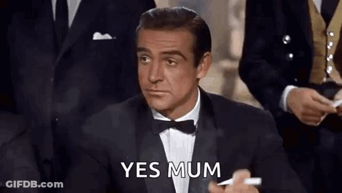 A Man In A Tuxedo And Bow Tie Is Holding A Cigarette And Says Yes Mum . GIF
