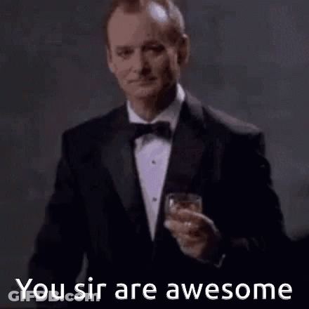 A Man In A Tuxedo And Bow Tie Is Holding A Glass Of Whiskey . GIF