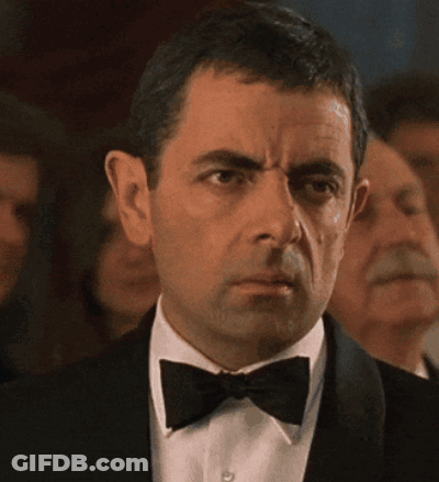 A Man In A Tuxedo And Bow Tie Is Looking At Something GIF