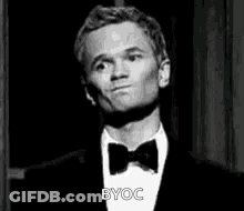 A Man In A Tuxedo And Bow Tie Is Making A Face . GIF