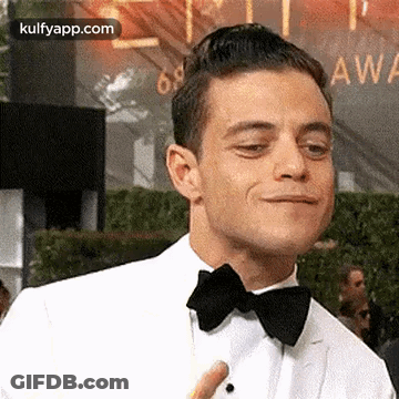 A Man In A Tuxedo And Bow Tie Is Making A Face . GIF