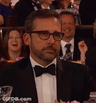 A Man In A Tuxedo And Bow Tie Is Sitting At A Table With Other People GIF