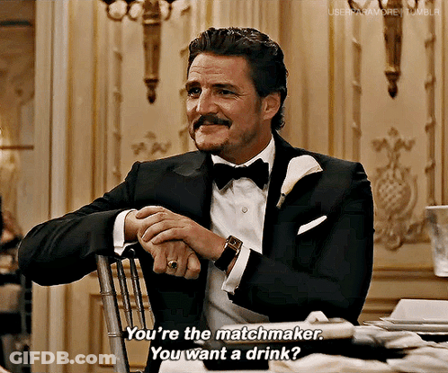 A Man In A Tuxedo And Bow Tie Is Sitting In A Chair And Talking To Someone . GIF