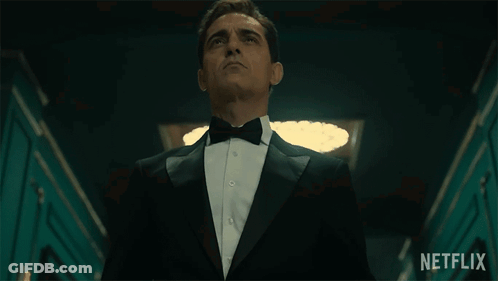 A Man In A Tuxedo And Bow Tie Is Standing In A Hallway With A Netflix Logo In The Background GIF