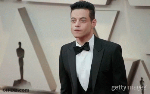 A Man In A Tuxedo And Bow Tie Is Standing In Front Of A Getty Image GIF