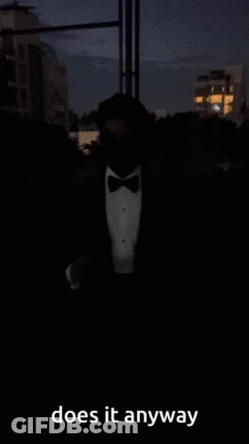 A Man In A Tuxedo And Bow Tie Is Standing In The Dark And Says Does It Anyway GIF