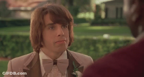 A Man In A Tuxedo And Bow Tie Is Talking To Another Man In A Park . GIF