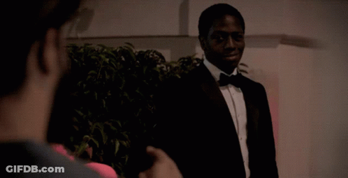 A Man In A Tuxedo And Bow Tie Is Talking To Another Man GIF