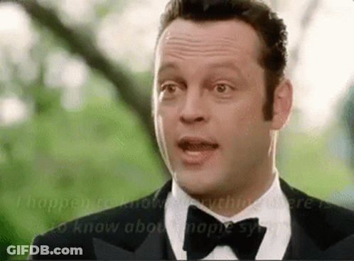 A Man In A Tuxedo And Bow Tie Is Talking To Another Man . GIF