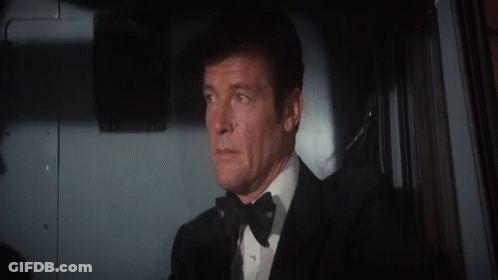 A Man In A Tuxedo And Bow Tie Looks Out Of A Window GIF