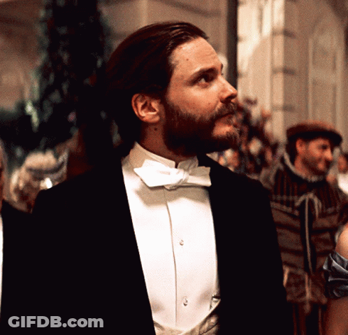 A Man In A Tuxedo And Bow Tie Looks To His Left GIF