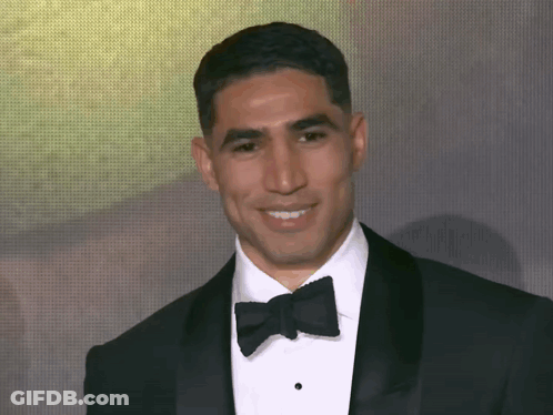 A Man In A Tuxedo And Bow Tie Smiles At The Camera GIF