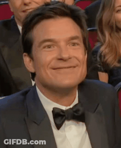 A Man In A Tuxedo And Bow Tie Smiles GIF