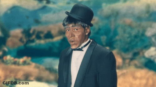 A Man In A Tuxedo And Bowler Hat Is Standing In Front Of A Painting GIF