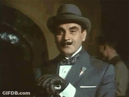 A Man In A Tuxedo And Hat Is Holding His Gloves GIF