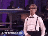 A Man In A Tuxedo And Suspenders Is Standing In Front Of A Phone Number GIF