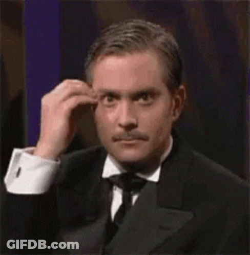 A Man In A Tuxedo And Tie Is Scratching His Forehead . GIF