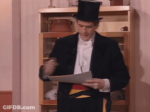 A Man In A Tuxedo And Top Hat Holds A Piece Of Paper GIF