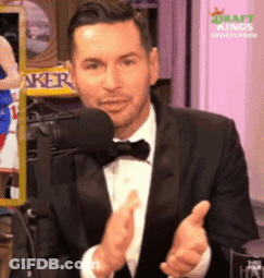 A Man In A Tuxedo Applauds In Front Of A Microphone GIF