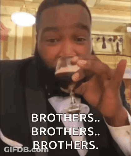 A Man In A Tuxedo Drinking From A Glass And Saying Brothers Brothers Brothers . GIF