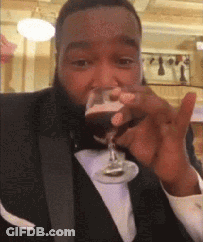 A Man In A Tuxedo Drinking From A Glass GIF