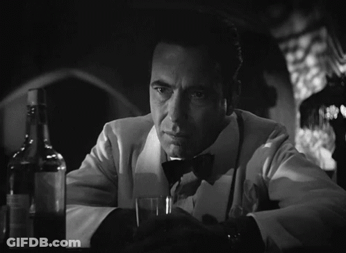 A Man In A Tuxedo Holds A Glass And A Bottle GIF
