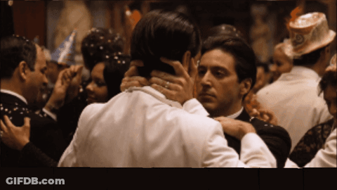 A Man In A Tuxedo Holds Another Man 'S Neck In A Crowd GIF