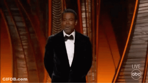 A Man In A Tuxedo Is Giving A Speech On A Stage . GIF