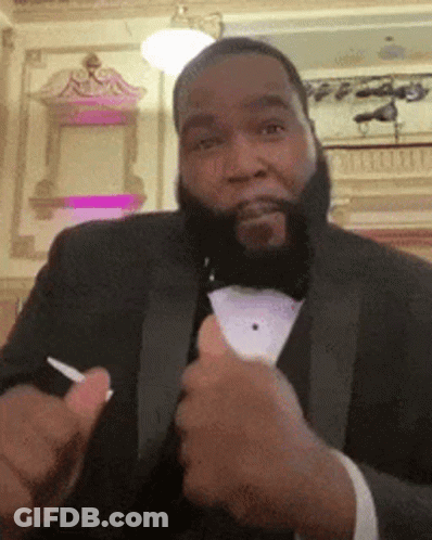 A Man In A Tuxedo Is Giving A Thumbs Up Sign GIF