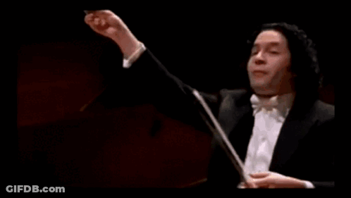 A Man In A Tuxedo Is Holding A Baton In Front Of A Green Bar With A Gold Coin On It GIF