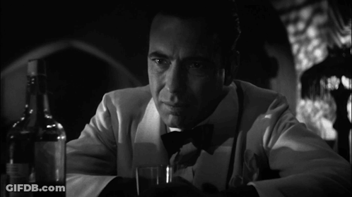 A Man In A Tuxedo Is Holding A Glass And A Bottle Of Whiskey GIF